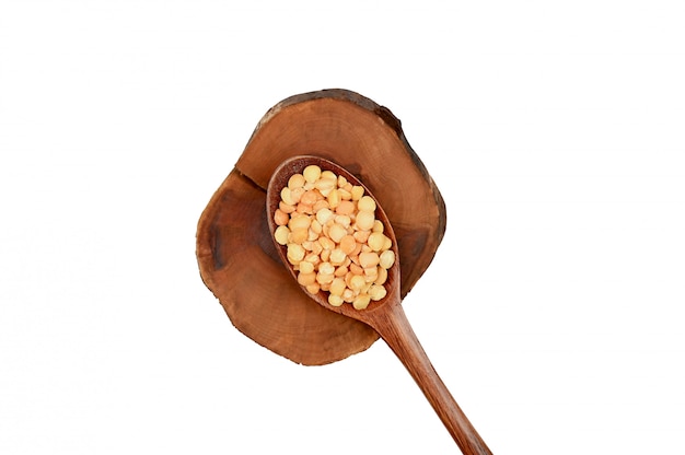 Wooden spoon and peas on a wooden board.