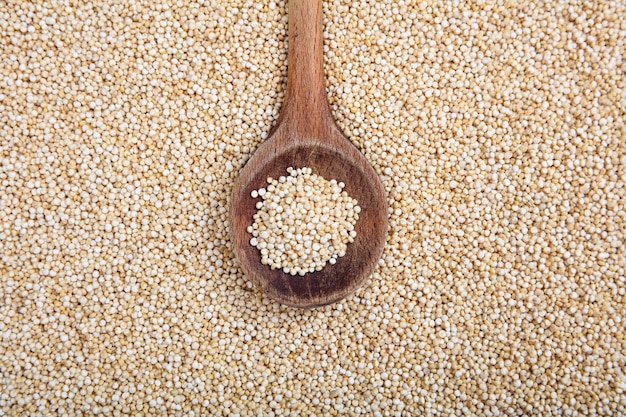 wooden spoon on raw white quinoa background