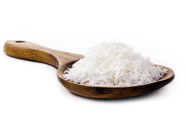 Wooden spoon rustic with grated coconut on white background with copy space, culinary ingredient