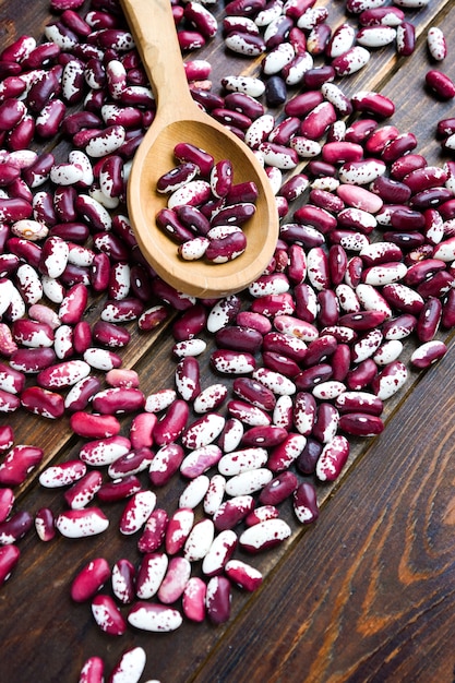 Cucchiaio e viola di legno con i fagioli dei punti su fondo di legno. fagioli ingoiati. verdure per un'alimentazione sana alimento biologico.