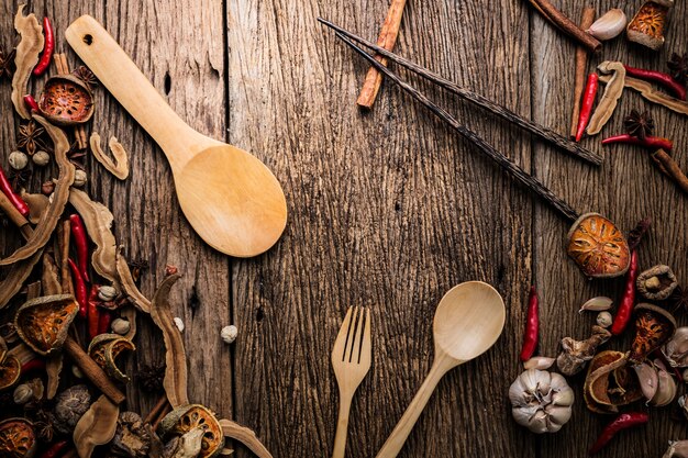 Cucchiaio di legno con l'ingrediente di erba asiatica sul pavimento di legno