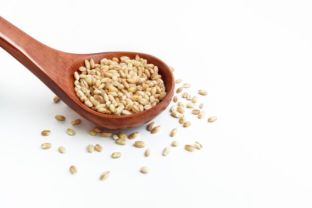 Wooden spoon with barley porridge on a white background
