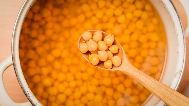 Cucchiaio di legno con ceci bolliti su una padella