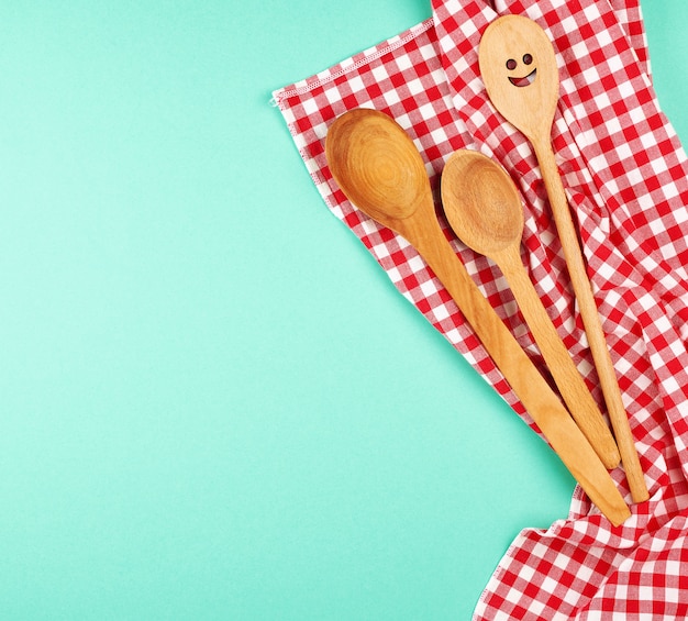 Wooden spoon with a carved face on a red kitchen towel