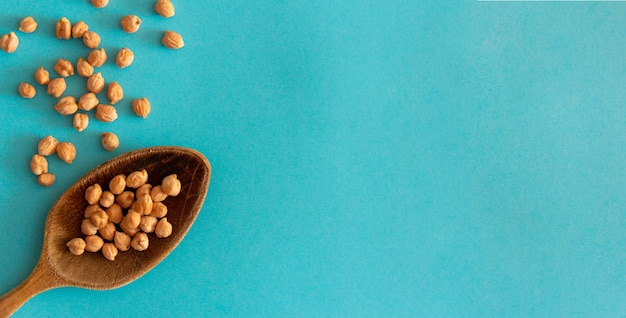 Wooden spoon with chickpeas on blue background. Top view. Flat lay. Copy space. Mediterranean food.