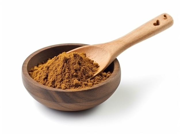A wooden spoon with cinnamon on it sits in a wooden bowl.