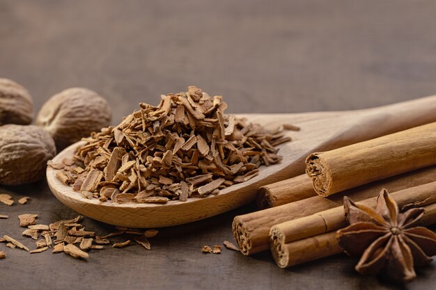 Foto cucchiaio di legno con cannella schiacciata rotoli di cannella anice stellato e noce moscata intera brown legno sfondo spazio copia