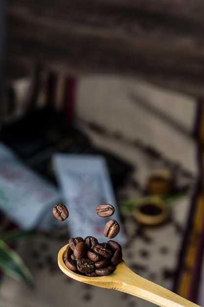 Foto cucchiaio di legno con chicchi di caffè che cadono