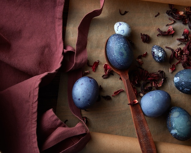 Wooden spoon with painted egg on a dark apron, flat lay