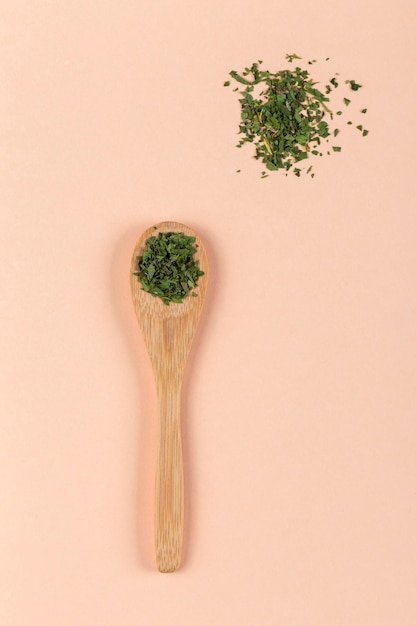 Wooden spoon with Parsley on pink background Parsley powder for seasoning food natural kitchen ingredients