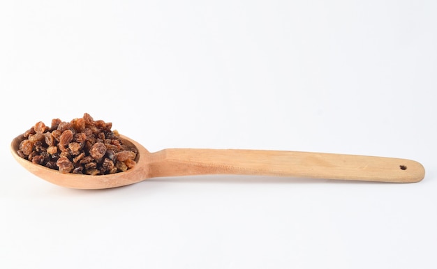 Wooden spoon with raisins on white background