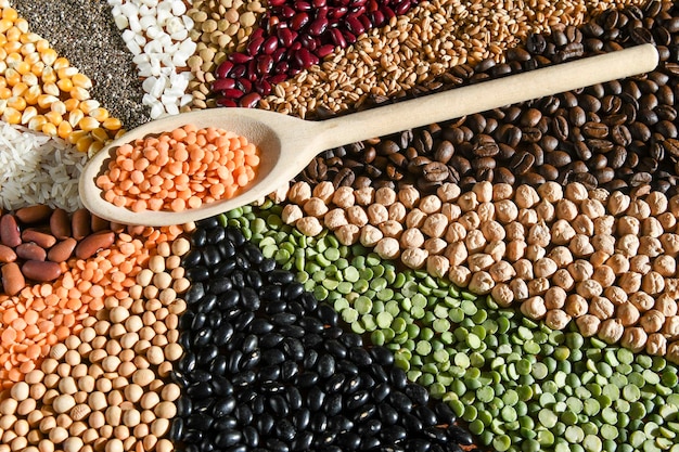 Wooden spoon with raw red lentils on various grain