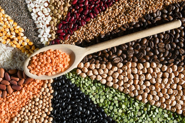 Wooden spoon with raw red lentils on various grain