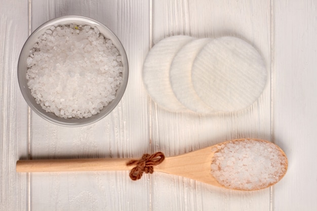 Wooden spoon with salt and cotton pads on white desk