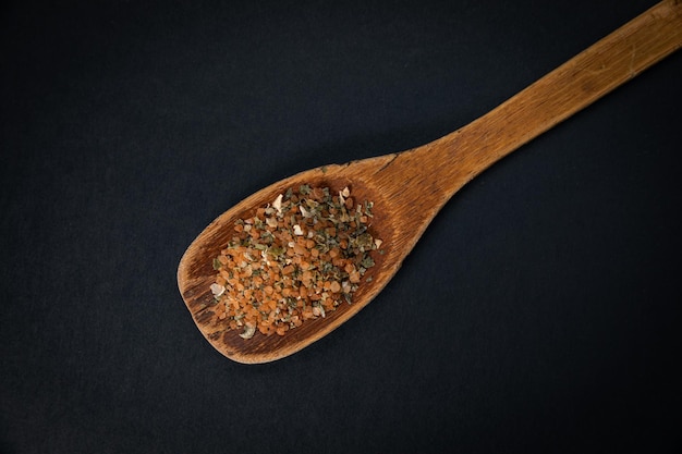 wooden spoon with salt and spices on a dark background