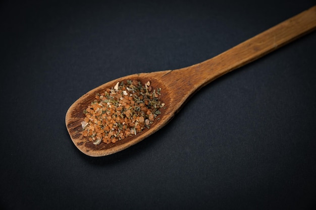 wooden spoon with salt and spices on a dark background