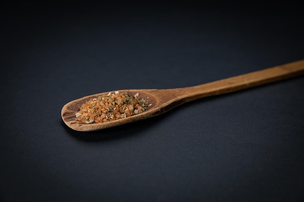 wooden spoon with salt and spices on a dark background