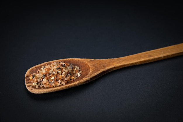 wooden spoon with salt and spices on a dark background