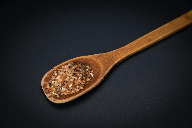 wooden spoon with salt and spices on a dark background