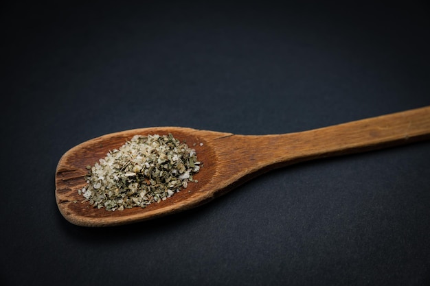 wooden spoon with salt and spices on a dark background