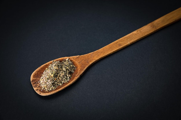 wooden spoon with salt and spices on a dark background