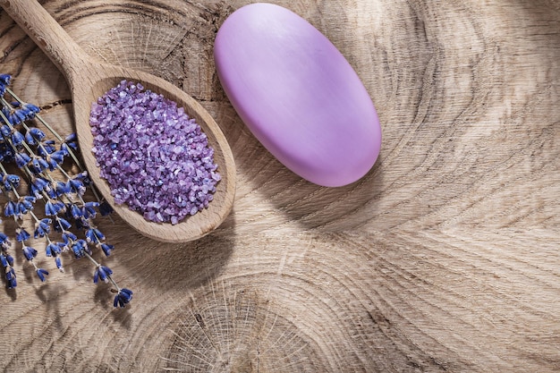 Il cucchiaio di legno con sale marino ha asciugato il pezzo di sapone della lavanda sul concetto di trattamento della stazione termale del bordo di legno