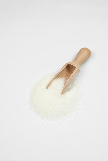 Foto cucchiaio di legno con zucchero su sfondo bianco
