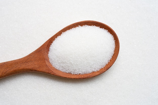 Wooden spoon with white granulated sugar. 