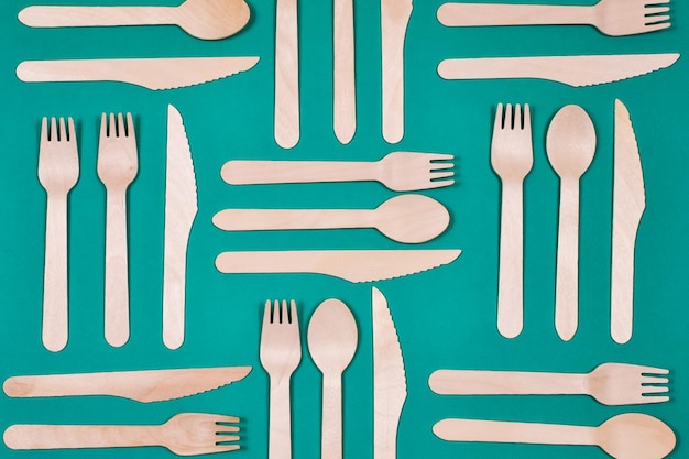 Wooden spoons forks knives on a green background pattern zero waste concept