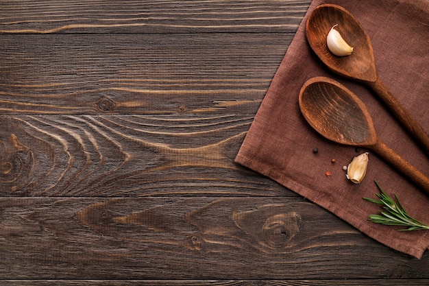 Wooden spoons, garlic and rosemary on wooden background