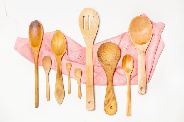 Wooden spoons on a pink napkin and on a marble background with copy space