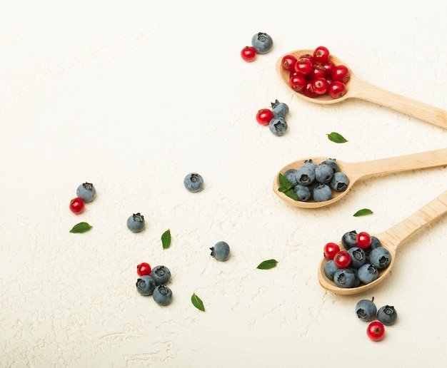 wooden spoons with currants and blueberries on a gray background