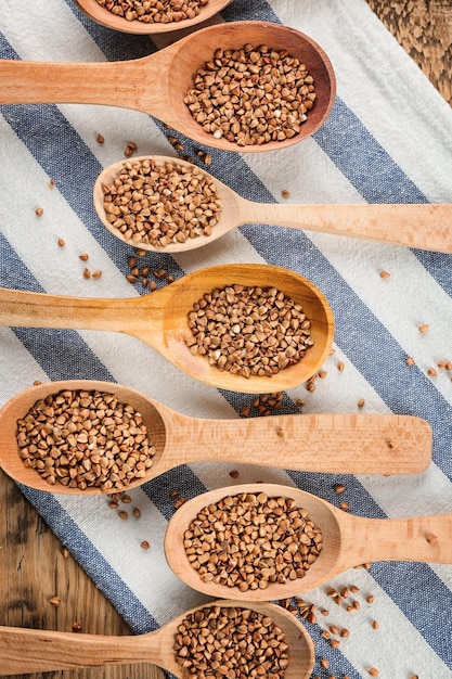 Wooden spoons with raw buckwheat on table