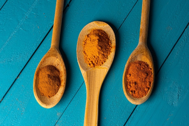 Wooden spoons with spices on a blue rustic wooden table