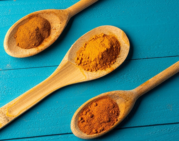 Wooden spoons with spices on a blue rustic wooden table