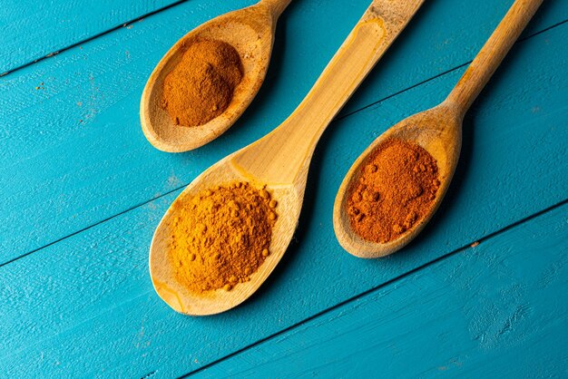 Wooden spoons with spices on a blue rustic wooden table