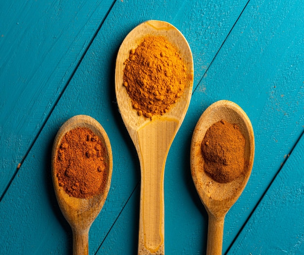 Wooden spoons with spices on a blue rustic wooden table