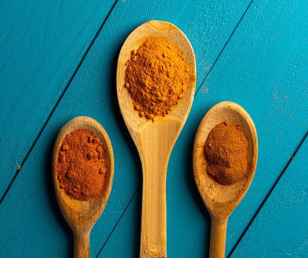 Wooden spoons with spices on a blue rustic wooden table