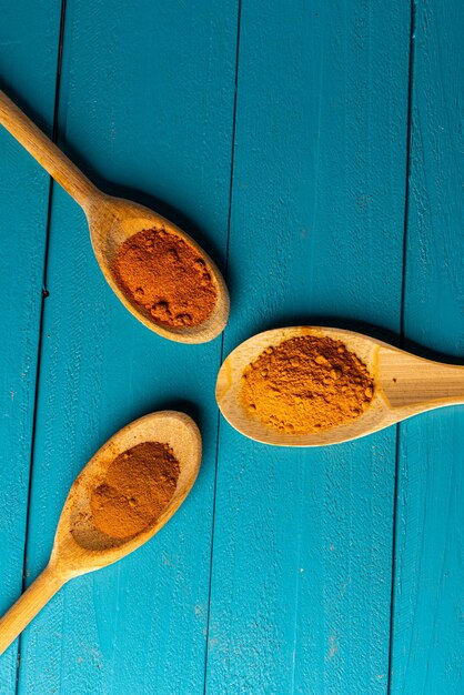 Wooden spoons with spices on a blue rustic wooden table