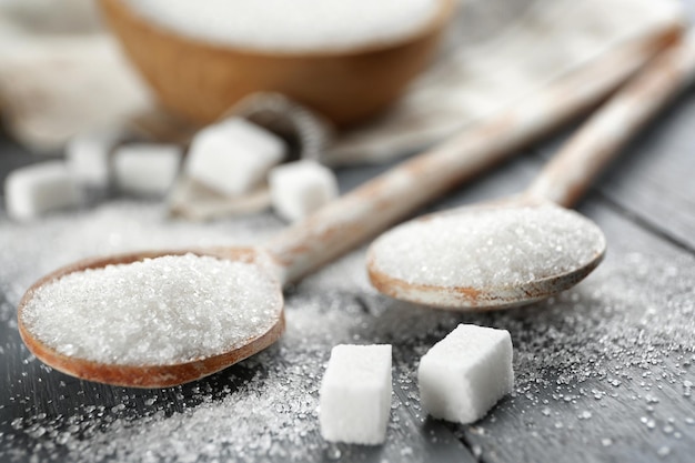 Wooden spoons with sugar on table closeup