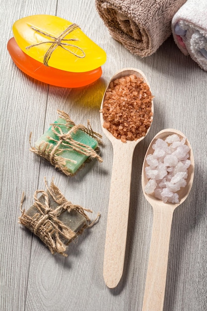 Wooden spoons with white and brown sea salt and handmade soap for bathroom procedures with towels