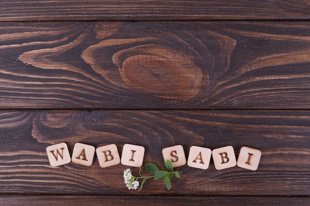 Wooden squares with letters. Inscription Wabi sabi. Dark wooden background. Copy space