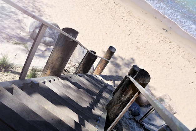 Wooden staircase descends down to the sandy sea beach in the morning