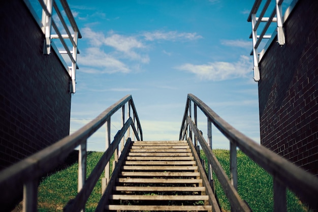 Wooden stairs on dike against blue sky