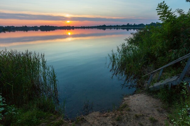 Wooden stairs to summer sunset lake