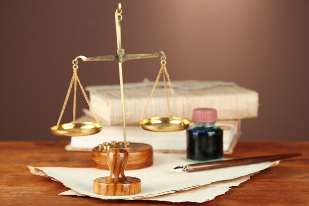 Wooden stamp, scales of justice and old papers on wooden table