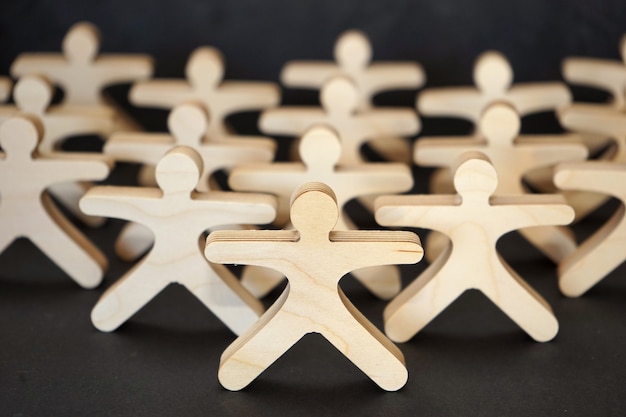 Wooden statuettes stand together on the black background