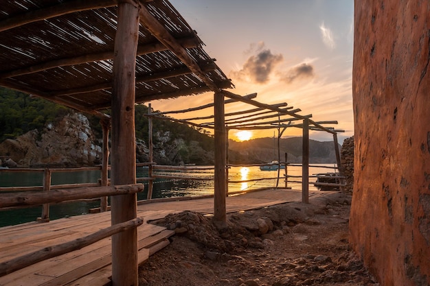 イビサ島の休暇の概念のベニラスで日没時のビーチハウスの木造構造物