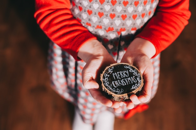 Foto ceppo di legno nelle mani dei bambini con le parole, buon natale