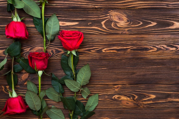 On a wooden surface are red roses